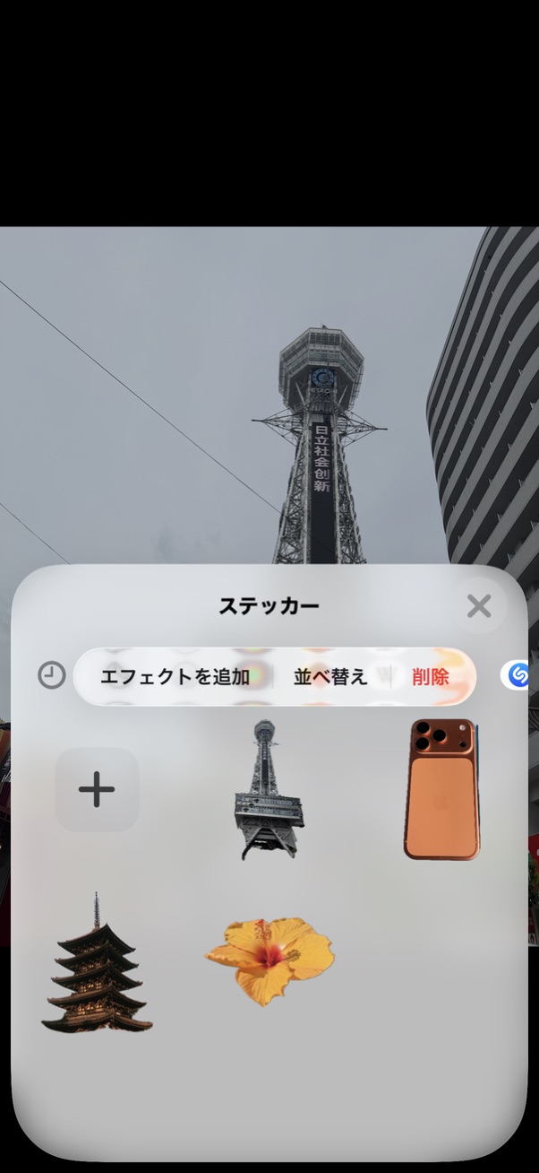塔の写真を背景に、建物などのステッカーとエフェクトを追加・並べ替え・削除のメニューが表示された画面