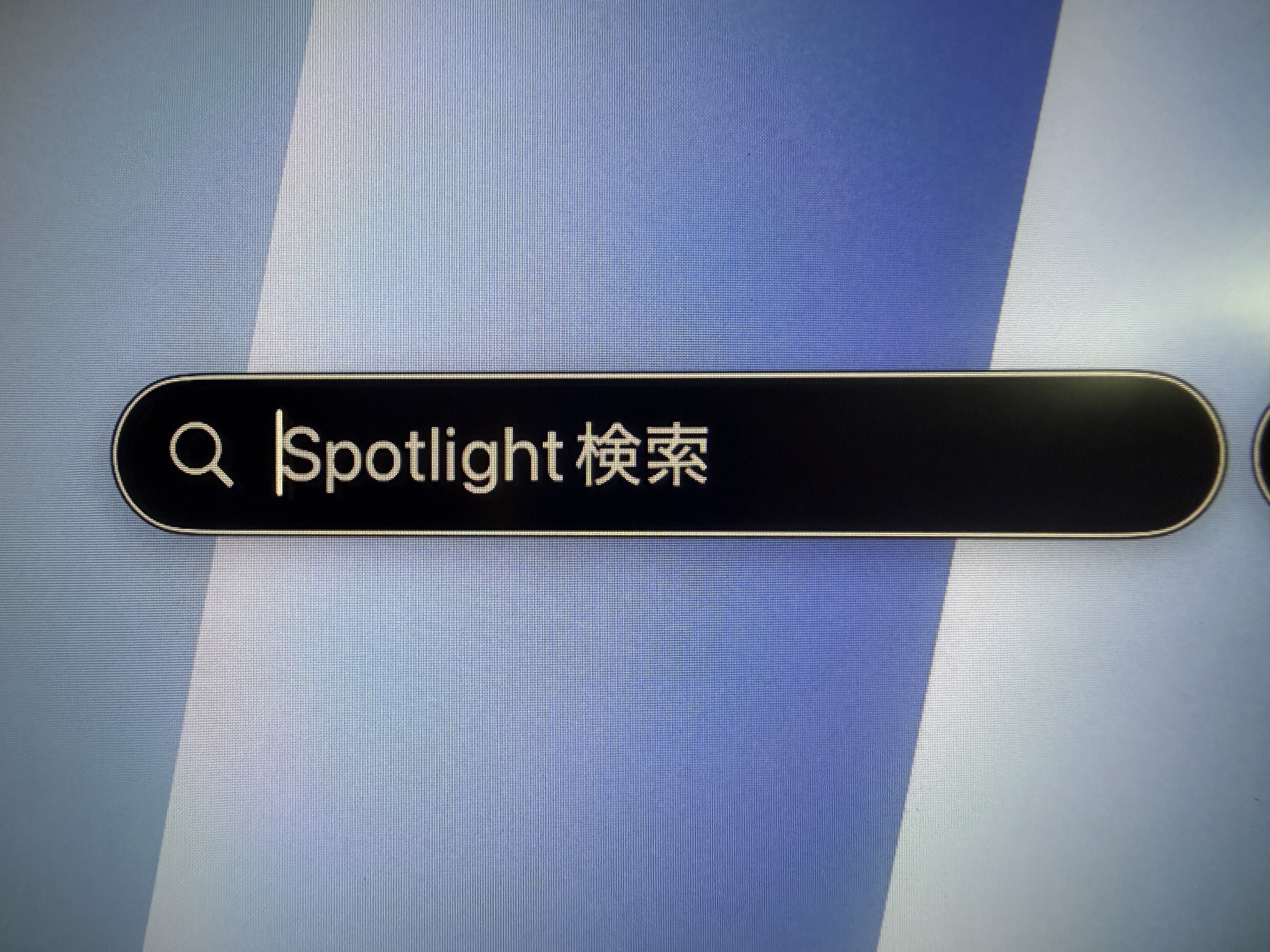 Macの画面を撮影した写真。虫眼鏡アイコンの隣に「Spotlight検索」と表示された入力前の検索欄